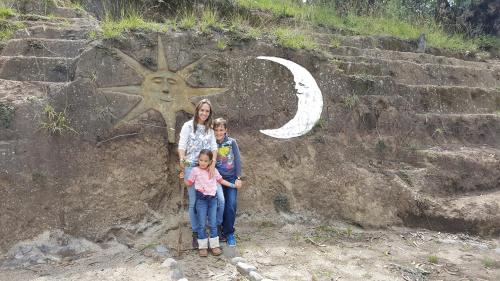 a woman and two children standing in front of a rock wall at Casa Hotel Loma Wasi en Cotacachi in Cotacachi