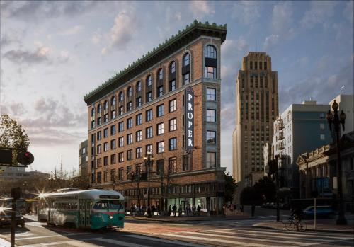 a green bus driving down a street in front of a building at San Francisco Proper Hotel, a Member of Design Hotels in San Francisco