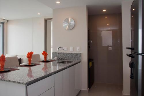 une cuisine avec deux lavabos et une horloge murale dans l'établissement Apartamentos Morros City Cartagena, à Carthagène des Indes