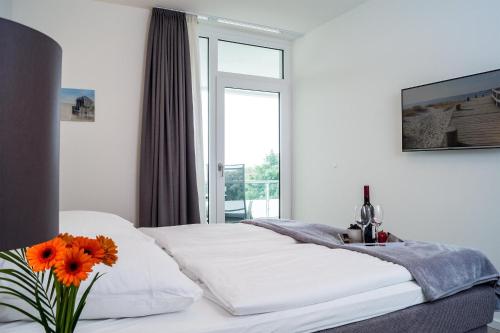 a bedroom with a bed with a vase of flowers at Südkap F-03 in Pelzerhaken