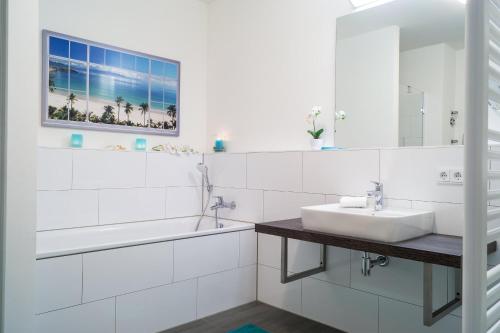 a white bathroom with a sink and a mirror at Südkap F-03 in Pelzerhaken