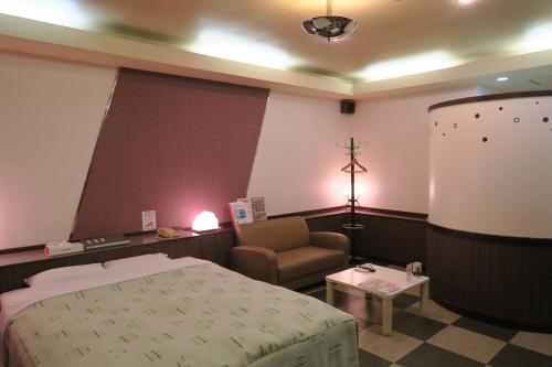 Habitación hospitalaria con cama y silla en Hotel Carnival (Love Hotel), en Miyaki