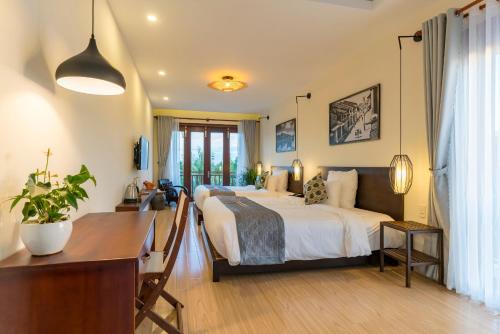 a bedroom with a bed and a desk in it at Riverside Hamlet Homestay & Villa in Hoi An