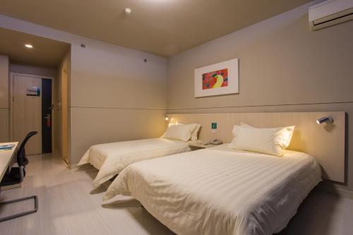 two beds in a hotel room with white sheets at Jinjiang Inn Baoji High-speed Rail Station in Baoji