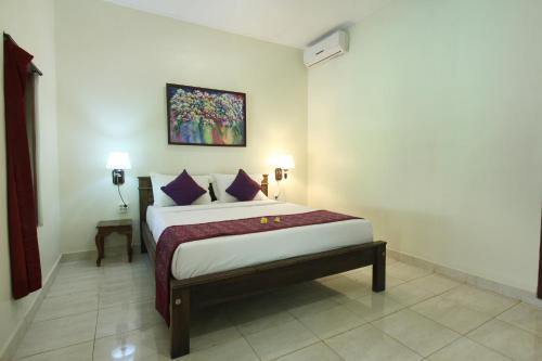 a bedroom with a bed and a painting on the wall at Nara Ubud Cottage by Mahaputra in Ubud