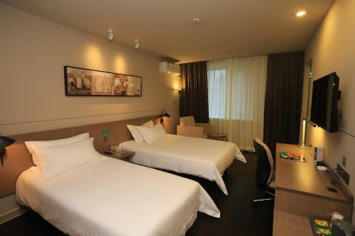 a hotel room with two beds and a television at Jinjiang Inn Select Chongqing Caiyuanba Railway Station in Chongqing