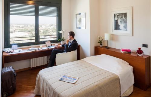 Ein Mann, der an einem Schreibtisch in einem Hotelzimmer sitzt. in der Unterkunft Cosmo Residence in Vimercate
