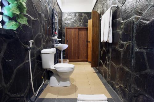 a bathroom with a toilet and a stone wall at Nara Ubud Cottage by Mahaputra in Ubud