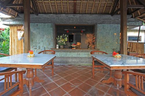 a patio with tables and chairs and a fireplace at Nara Ubud Cottage by Mahaputra in Ubud