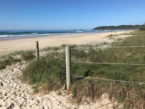 a fence on a beach with the ocean in the background at Tallow Beach Motel in Byron Bay