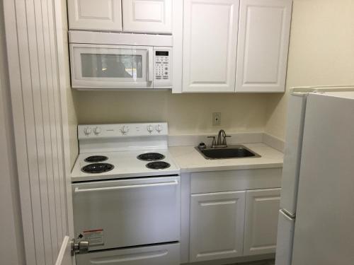 a white kitchen with a stove and a microwave at Belfair Motel in Belfair