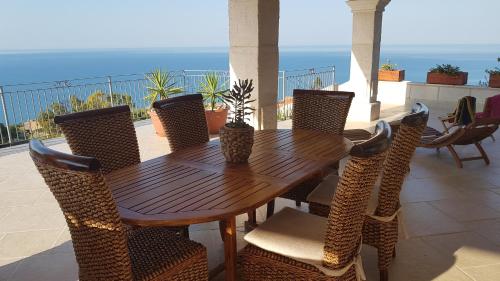a wooden table and chairs with the ocean in the background at B&B Terrazze Chiaramontane in Marina di Palma