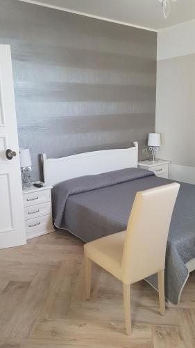 a bedroom with a bed and a white chair at B&B Terrazze Chiaramontane in Marina di Palma