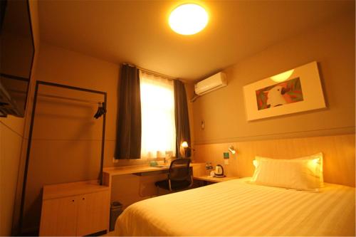 a bedroom with a bed and a desk and a window at Jinjiang Inn Changzhi Bayi Square in Changzhi
