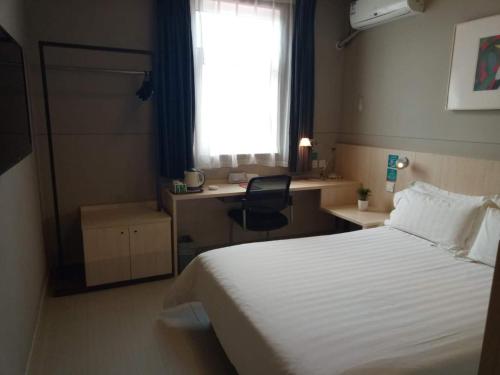a hotel room with a bed and a desk and a window at Jinjiang Inn Changzhi Bayi Square in Changzhi
