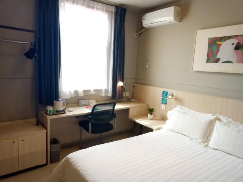 a bedroom with a bed and a desk and a window at Jinjiang Inn Changzhi Bayi Square in Changzhi