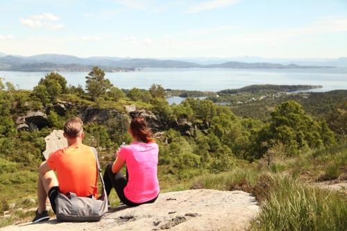 a man and a woman sitting on a rock looking at the water at Panorama Hotell & Resort in Steinsland