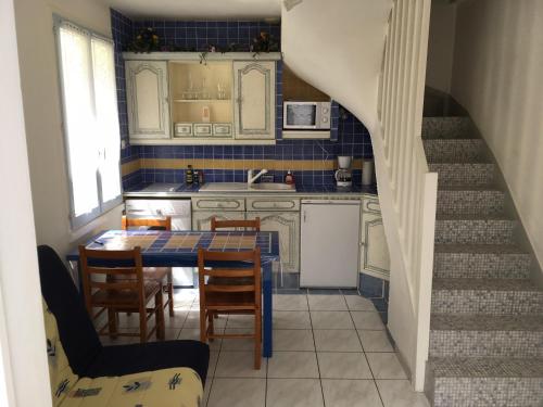 eine Küche mit einem Tisch und Stühlen sowie eine Treppe in der Unterkunft Maison vacances Noirmoutier Barbatre in Barbâtre
