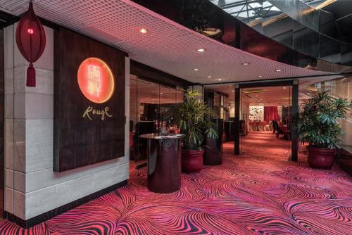 a restaurant with a red carpeted floor with potted plants at Regal Airport Hotel in Hong Kong