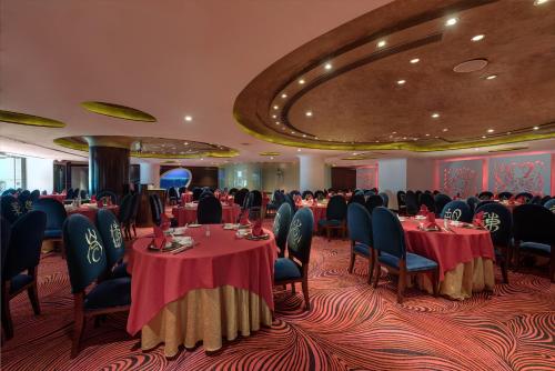 a banquet room with tables and chairs and people sitting around them at Regal Airport Hotel in Hong Kong
