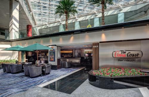 a restaurant with tables and chairs and palm trees at Regal Airport Hotel in Hong Kong