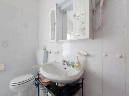 a white bathroom with a sink and a toilet at Tolasudolsa Rooms, Breakfast & Mountain Bike in Compiano