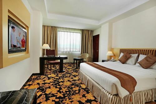 a hotel room with a bed and a desk at Rocky Plaza Hotel Padang in Padang