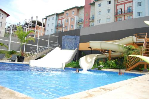 a pool with a water slide and people in the water at Veredas do Rio Quente Flat in Rio Quente