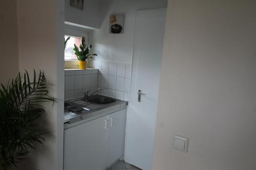 Elle comprend une petite cuisine blanche avec un évier et une fenêtre. dans l'établissement Apartment am Blücherplatz, à Kiel