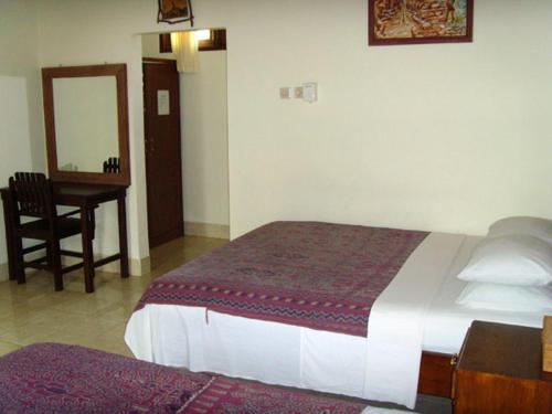 Schlafzimmer mit einem Bett, einem Schreibtisch und einem Spiegel in der Unterkunft Rumah Saga in Gili Trawangan