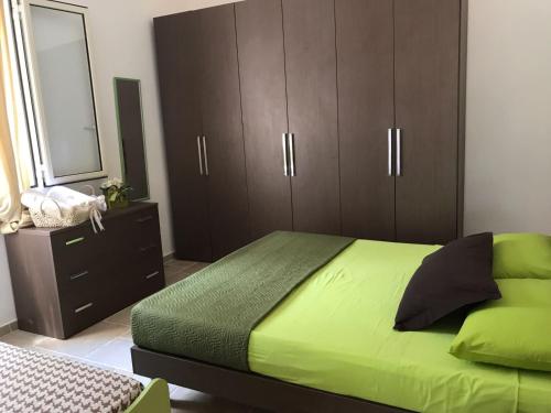 サンタ・カテリーナ・ディ・ナルドにあるCasa Vacanza Elvira Porto Selvaggioのベッドルーム(緑のベッド1台、茶色のキャビネット付)