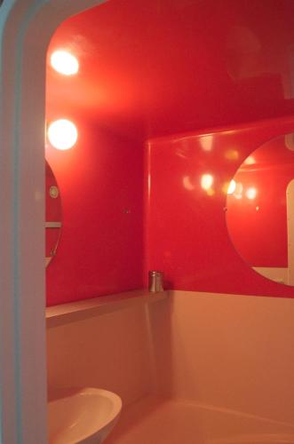 La salle de bains est pourvue de murs rouges et de toilettes blanches. dans l'établissement PIERRA MENTA ARC 1800 Studio Appartement - 5 per, à Arc 1800