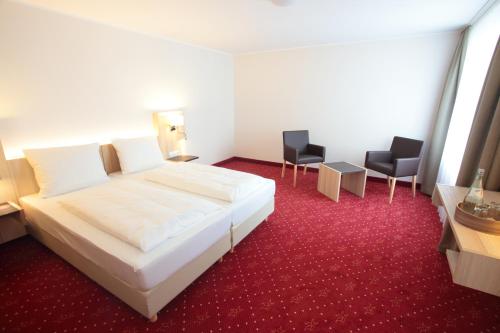 Hotel zur Schloß-Schenke في نيوفيد: غرفة الفندق بسرير ابيض وكرسيين