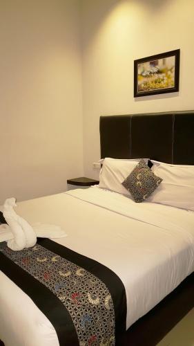 a bedroom with a large white bed with a black headboard at Sunrise Hotel Jombor Jogja in Yogyakarta