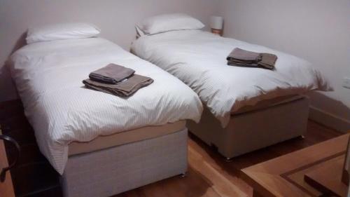 2 camas con toallas encima de ellas en un dormitorio en Jasmine Cottage en Llangollen