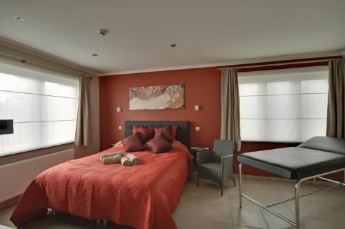 a bedroom with a red bed and a chair at B&B Noord-Zuid in Zonhoven
