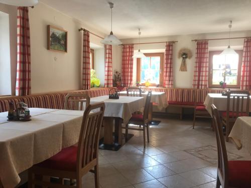 a dining room with tables and chairs and windows at Gasthof Wacht in Untertilliach