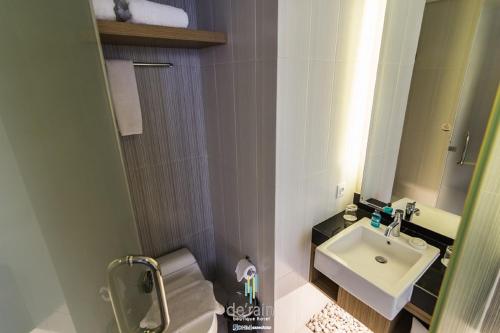Baño pequeño con lavabo y espejo en De'Rain Hotel Bandung, en Bandung