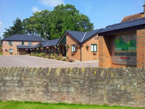 a brick building with a fence in front of it at Deangate Motel in Lydney