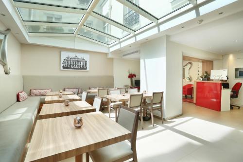 une salle à manger avec des tables et des chaises en bois dans l'établissement Le Grand Hôtel de Normandie, à Paris