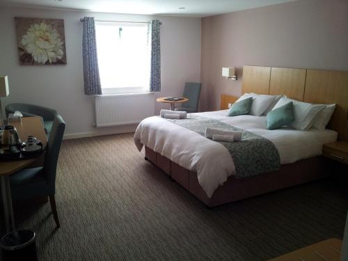 Habitación de hotel con cama, escritorio y ventana en Deangate Motel, en Lydney