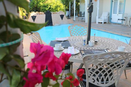 a table with pink flowers next to a pool at Paradiso Guesthouse & Self-catering Cottage in Cape Town