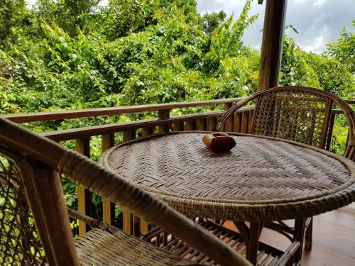 a wicker table and chairs on a balcony with trees at Kingfisher Ecolodge in Ban Kian-Ngông