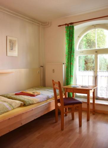 a bedroom with a bed and a table and a window at Pension zur Wartburg in Görlitz