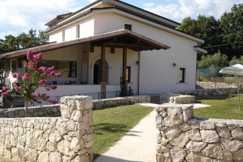 a white house with a stone wall at Agriturismo Casale Sera in Fontana Liri