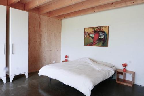a bedroom with a bed and a painting on the wall at VierVaart Studio appartement in Groede