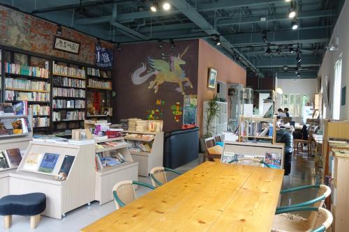 a book store with a wooden table and chairs at REST Book & Bed in Puli