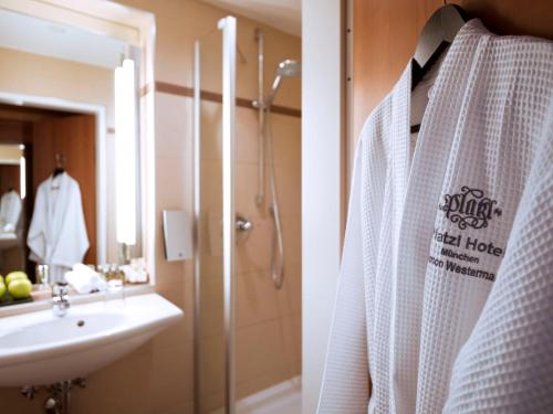 ein Bad mit einer Dusche und einem weißen Bademantel in der Unterkunft Platzl Hotel - Superior in München
