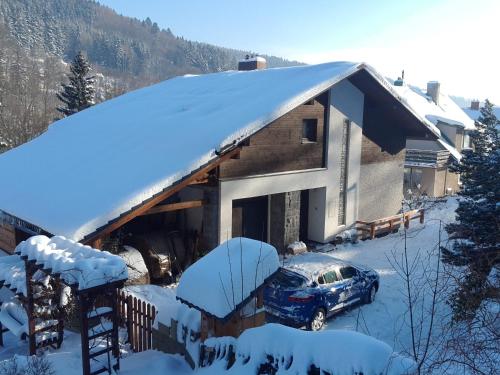 a house with a car parked in the snow at Ubytování - Černá hora II in Svoboda nad Úpou