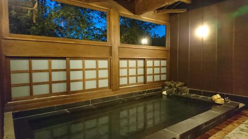 a swimming pool in a room with windows at Kurokawa Onsen Ryokan Ichinoi in Minamioguni